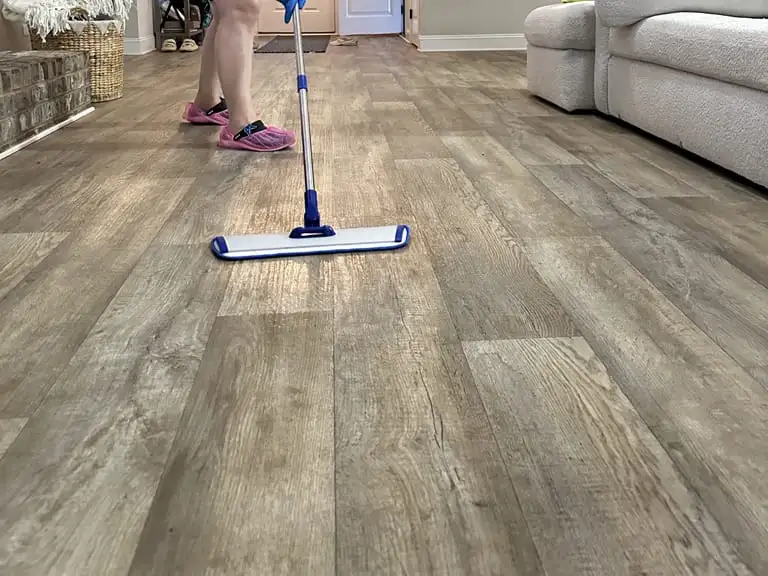 Cleaner using a flat microfiber mop on a wood-look floor in a living room
